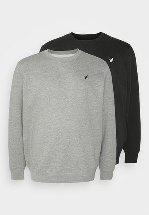 Dos sudaderas de cuello redondo en gris y negro. Están hechas de una tela suave con puños y dobladillos acanalados; cada una presenta un sutil logo en el pecho.