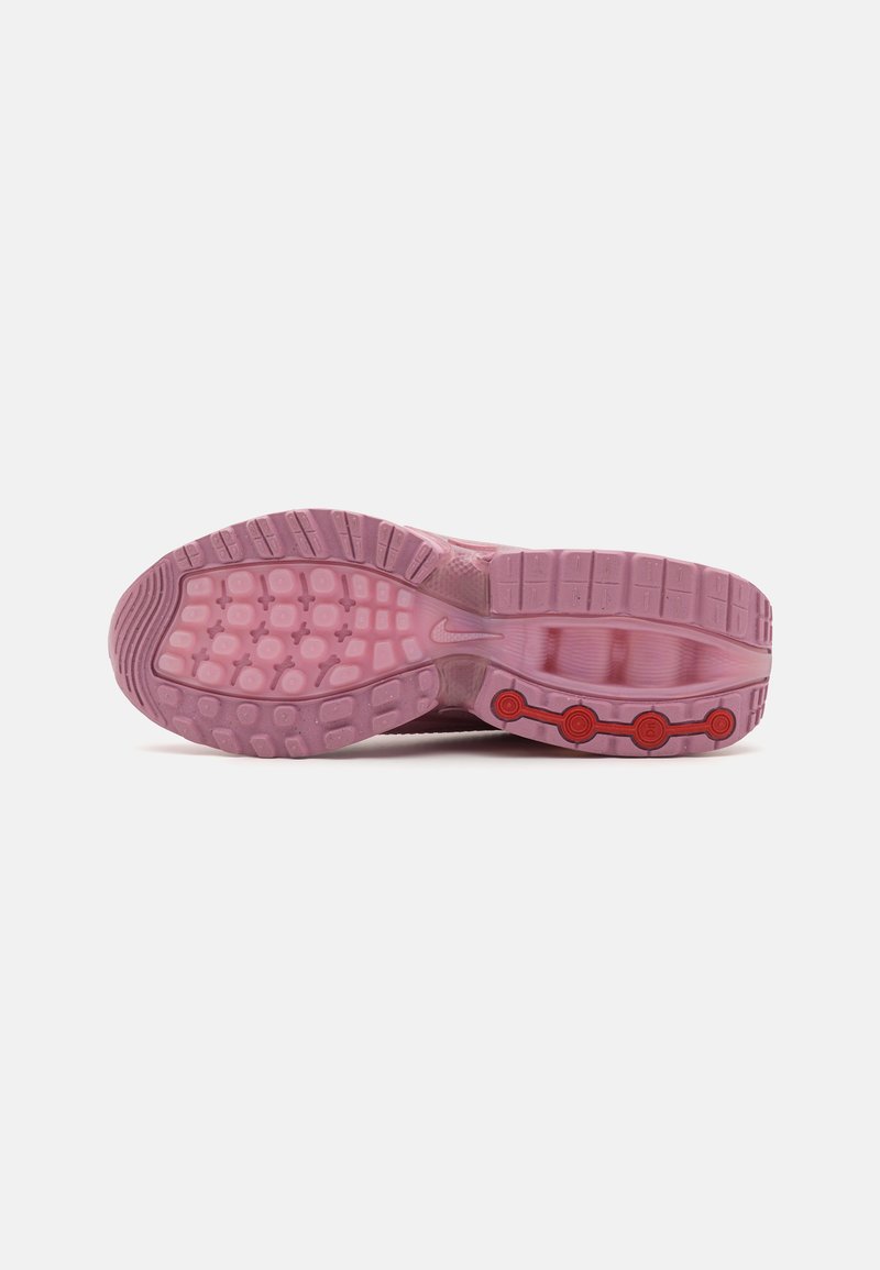Nike-Schuhsohle in Pink mit strukturiertem Griff, ausgestattet mit runden roten Akzenten und einer glatten, flexiblen Struktur für Traktion und Unterstützung.