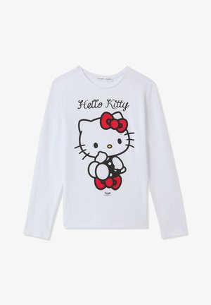 Biała koszula z długim rękawem z grafiką Hello Kitty z czerwoną kokardą i sukienką w kropki, z czarnymi i czerwonymi akcentami.