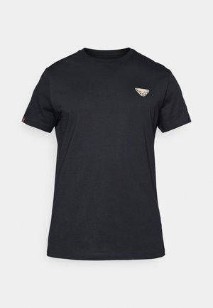 Svart bomull T-skjorte med korte ermer, rund hals og et beige emblem med et stilisert ansikt på øvre venstre side.