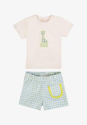 Maglietta crema a maniche corte per toddler con applicazione di giraffa blu a quadretti vichy, abbinata a pantaloncini a quadretti bianchi e blu con tasca rifinita gialla.