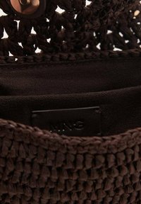 Sac à main tissé marron avec un extérieur texturé, doté d'une doublure en tissu et d'une petite étiquette en cuir marquée "MNG" à l'intérieur.
