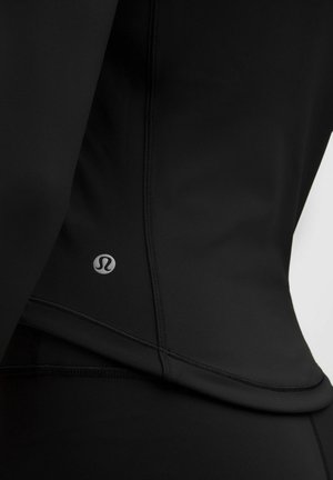 Zwart sporttop gemaakt van rekbare stof, met een slim fit, vlakke naden en een klein logo aan de linkerkant nabij de zoom.