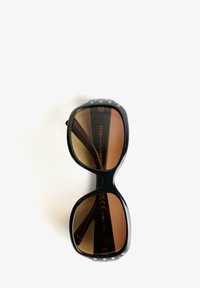 Black sunglasses with oversized frames, gradient brown lenses, and decorative rhinestones on the upper edge of the frame.