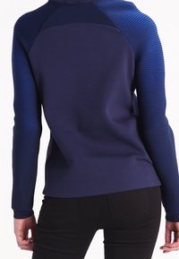 Mörkblå tröja med texturerade ribbade ärmar, designad med en figurnära passform och slät tygkvalitet, med rundad halsringning och långa ärmar.