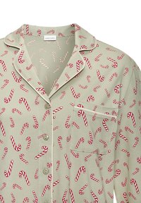 Langermet, lys grønn pysjamasoverdel med rødt og hvitt polkagrismønster. Har en lomme, knappestenging og kontrasterende piping langs kantene.