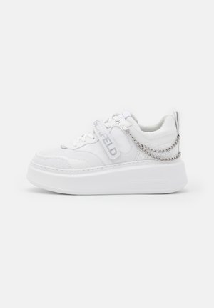 Sneaker plateforme blanche avec semelle épaisse, panneaux en mesh et cuir, bride marquée sur les lacets et détail chaîne argentée autour du talon.