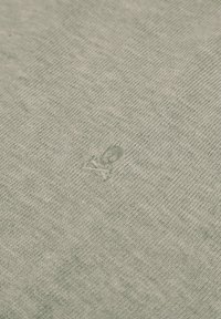 Miękka szara tkanina o delikatnej, dzianinowej fakturze z małą, wytłoczoną literą „P” blisko środka.