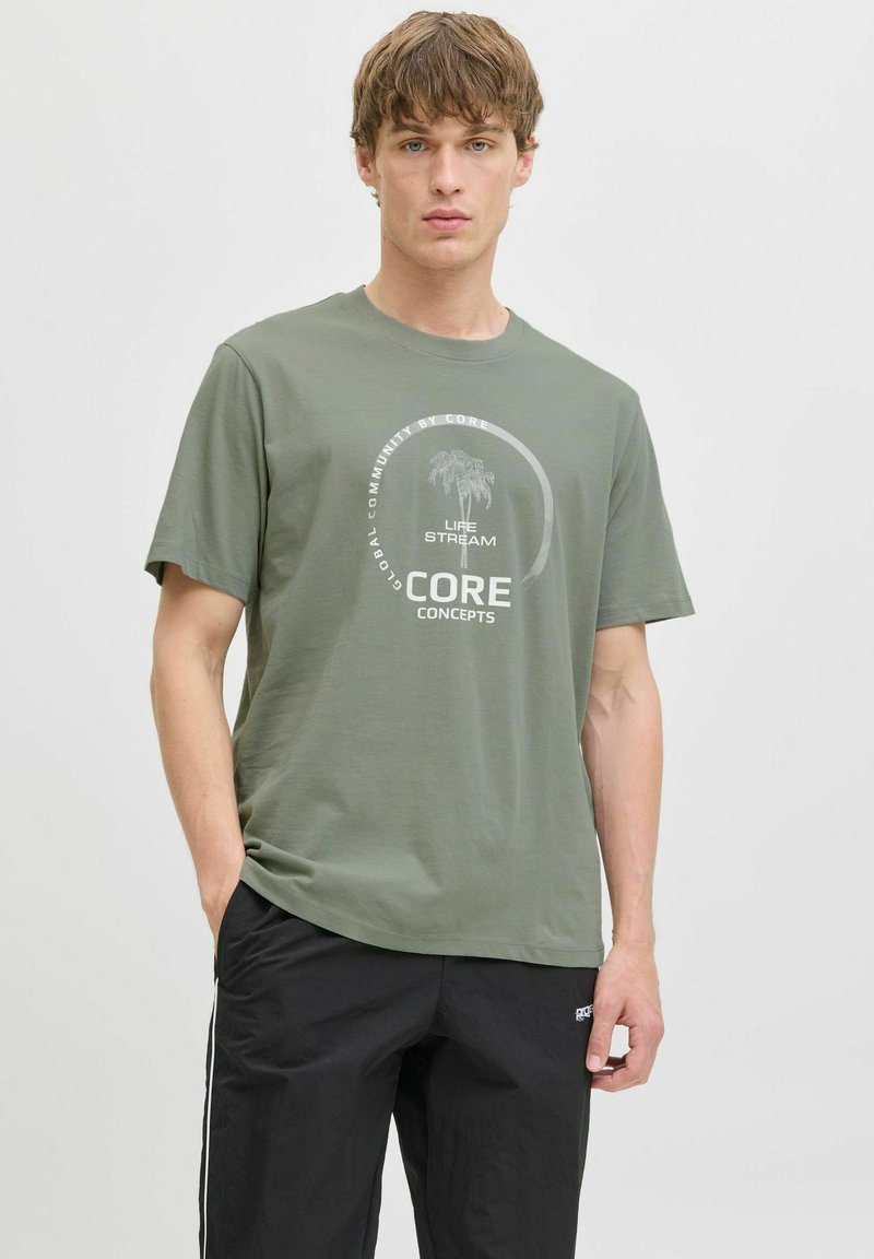 Camiseta de algodón verde oliva de manga corta, con un diseño gráfico circular en blanco y un detalle de palma en el centro.
