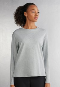 Helles graues Langarmshirt aus weichem Stoff mit Rundhalsauschnitt und lockerer Passform, das minimale Nähdetails und kein Muster aufweist.