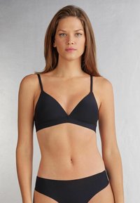 Svart triangulär bh med tunna justerbara band, sömlöst design och mjukt tyg. Matchas med svarta trosor.