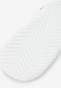 Valkoinen kenkäsole, jossa on aaltoileva tekstuuri ja sileä pinta, ei näkyviä logoja tai kuvioita. Muotoilu korostaa minimalismia.