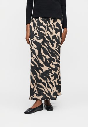Béžová sukňa strednej dĺžky s čiernym abstraktným zvieracím vzorom, doplnená čiernym tričkom s dlhým rukávom a čiernymi balerínami.