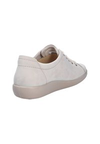 Lichtbeige casual sneaker met afgeronde neus, vetersluiting, gevoerde kraag en flexibele zool, gezien vanuit een achterzijaanzicht.