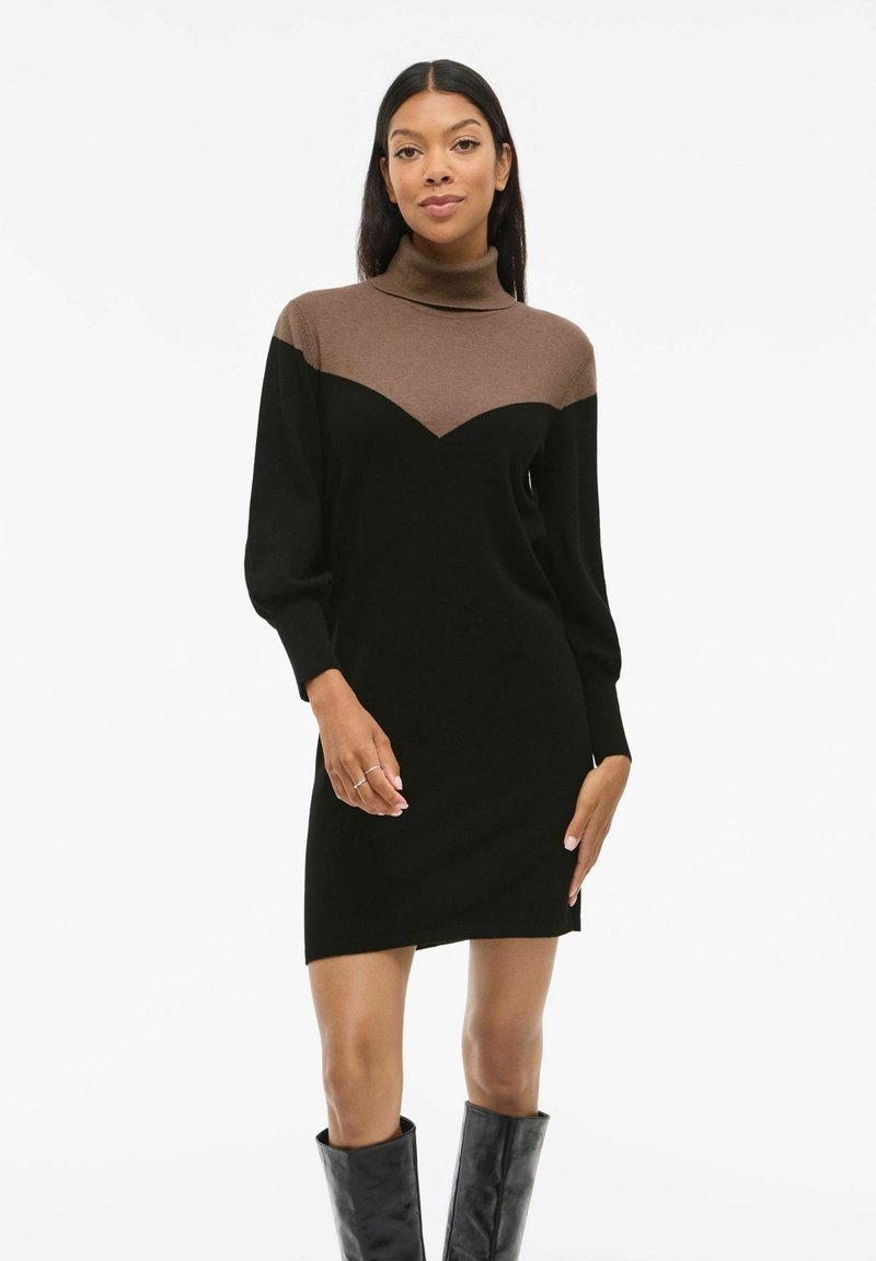 Robe en tricot avec un design en blocs de couleur marron et noir, col haut, manches longues et une silhouette ajustée. Texture lisse, détails minimaux.