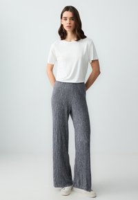 Grijze, geribbelde wijde broek met hoge taille, gecombineerd met een strakke witte T-shirt met korte mouwen; casual stijl met een zachte textuur.