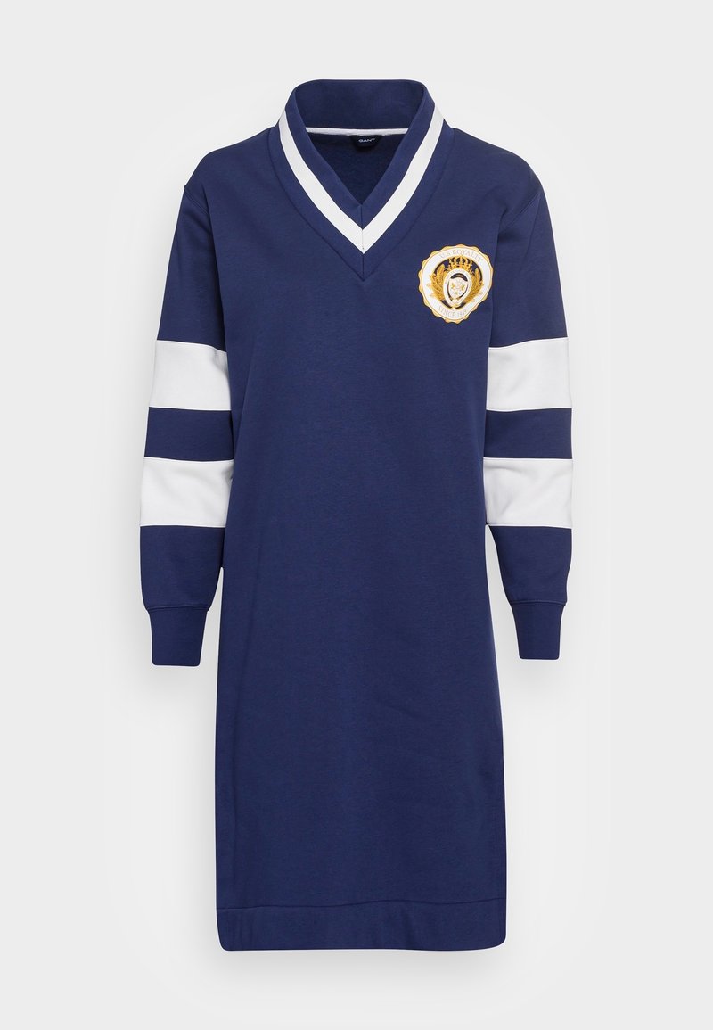 Vestido sudadera azul marino con rayas blancas en las mangas, cuello en V y un emblema bordado redondo con un escudo de león. Material de mezcla de algodón.