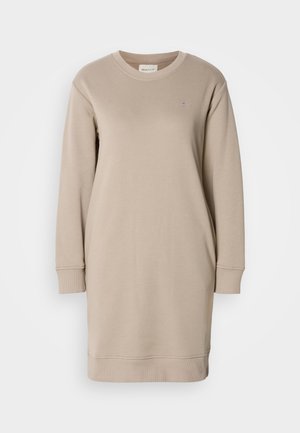 Beige collegepuku, jossa on pitkät hihat, pyöreä kaula-aukko ja ribattu resori. Rinnassa pieni logo, valmistettu pehmeästä kankaasta.