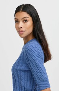Blauer gestrickter Pullover mit strukturierten Zopfmustern und kurzen Ärmeln. Gerippte Bündchen und Saum, glattes Material, figurbetonte Silhouette.