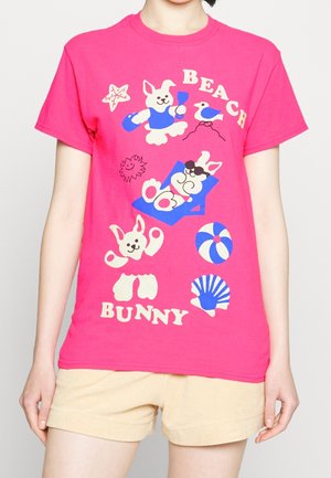 Felroze T-shirt met speelse strandthema-konijnillustraties, inclusief een liggend konijn, een zeester, een strandbal en schelpen.