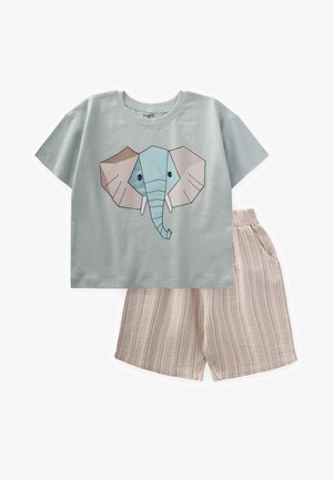 Gaiši zils kokvilnas T-krekls ar ģeometrisku ziloņa dizainu; kombinēts ar bēšiem svītrainiem šortiem, kas izgatavoti no mīkstas auduma.