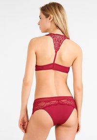 Bordeaux lingerieset met een kanten achterkant op de beha en bijpassende kanten accenten op de broekjes, uitgevoerd in een gladde stof en met een racerback ontwerp.