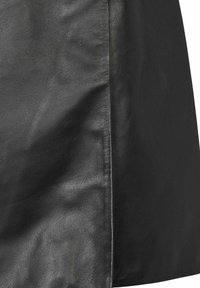 Κοντινή λήψη μαύρου δερμάτινου υφάσματος με ορατή υφή κόκκων και ραφή που τρέχει κατακόρυφα κοντά στο κέντρο.
