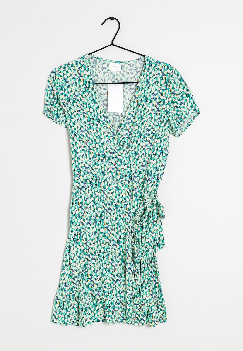 Robe portefeuille à manches courtes imprimée de fleurs vertes, blanches et bleues, suspendue sur un cintre noir contre un fond blanc.