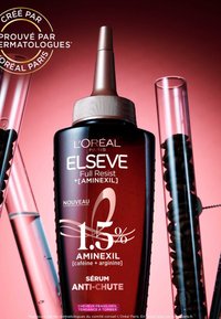 Bouteille bordeaux foncé avec un embout effilé, étiquetée "L'Oréal Paris Elseve Full Resist." Présente des accents dorés et contient un sérum contre la chute des cheveux.