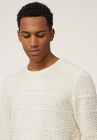 Cremfarbener gestrickter Pullover mit einem strukturierten Zickzack- und Gittermuster, rundem Halsausschnitt und lockerer Passform.