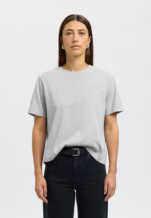 Szara bawełniana koszulka z krótkim rękawem, okrągłym dekoltem i luźnym krojem. Noszona z wysokim stanem czarnych dżinsów i czarnym paskiem. Gładka faktura.