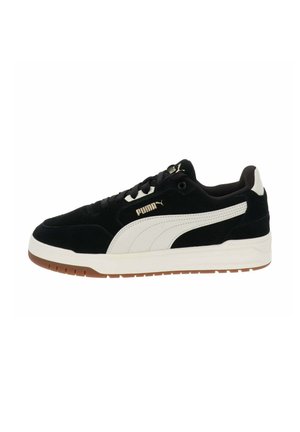 Zapatillas de ante negras con acentos en cuero blanco y suela de goma beige. Presentan un diseño de cordones y una sutil marca en el costado.