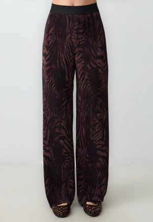 Pantaloni larghi a pieghe di colore scuro con motivo zebra, dotati di una fascia nera in vita e una consistenza liscia. Schema di colori marrone e nero.