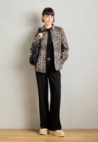 Jakke med leopardmønster, svart topp, vide svarte bukser, beige platåsko og en svart veske. Glatt tekstur med løs passform.