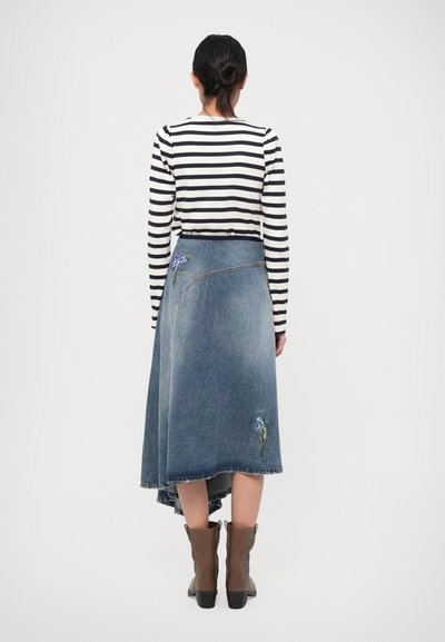Denim omslagskjørt med en høy-lav hem, prydet med blå blomsterbroderi. Bæres sammen med en svart og hvitstripet langermet topp og brune ankelstøvler.