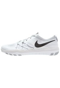 Białe buty sportowe z siateczkową cholewką, szarymi akcentami i wyraźnym czarnym logo Nike. Podeszwa ma fakturę z wypustkami zapewniającymi przyczepność.