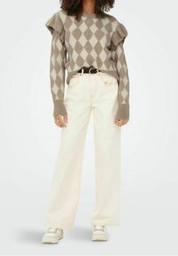 Pull beige en maille avec un motif argyle, manches à volants, associé à un pantalon large couleur crème clair et des baskets blanches. Design ceinturé.