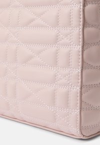 Κουβερτισμένη ροζ δερμάτινη τσάντα με λευκή ραφή, σε ορθογώνιο σχήμα και λείο υλικό. Χωρίς ορατές μεταλλικές λεπτομέρειες ή διακοσμητικά.