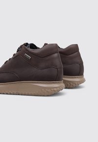 Chaussures décontractées en cuir marron avec des semelles en caoutchouc texturé beige, vues de l'arrière et légèrement de côté.