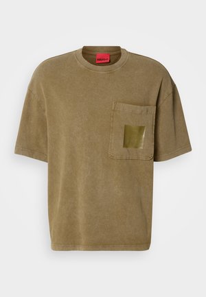 Oversized short-sleeve brown T-shirt with chest pocket featuring a shiny square detail, crew neckline, and red HUGO label inside collar.