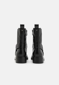 Black leather ankle boots with a smooth finish, featuring a strap across the midsole and a low, sturdy heel. Zipper detail at the back.