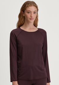 Langshirt in donker bordeaux stof, met een ronde hals en raglanmouwen, met een gladde, rekbare textuur.