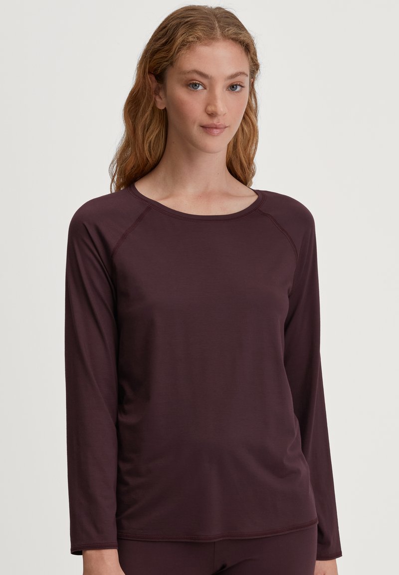 Langshirt in donker bordeaux stof, met een ronde hals en raglanmouwen, met een gladde, rekbare textuur.