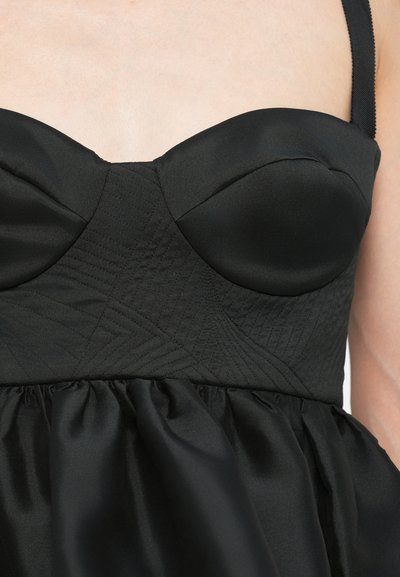 Black dress with a fitted bodice featuring padded cups and textured panel. Skirt is gathered, creating a flowing silhouette.