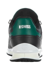 Fekete és zöld K-Swiss tornacipő párnázott sarokkal, sima bőr anyagból, hálós részletekkel és fehér talppal. A saroknál a logó látható.