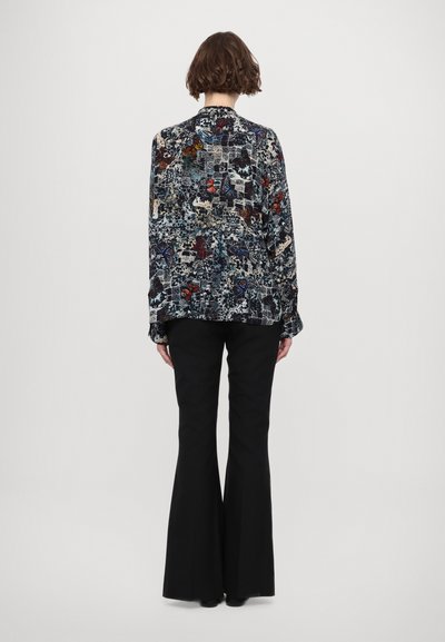 Floral patterned blouse with a loose fit, long sleeves, and a rounded collar, paired with black flared pants. Textured fabric with vibrant colors.