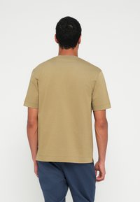 Koszulka khaki z krótkimi rękawami, okrągłym dekoltem i prostym krojem. Wykonana z bawełny, o subtelnym fakturowaniu. Boczne rozcięcia na dole.