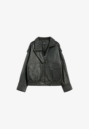 Czarna skórzana kurtka o luźnym kroju, z szerokim kołnierzem i dwiema przednimi kieszeniami. Tekstura jest gładka, z lekko błyszczącym wykończeniem i elastycznym pasem.