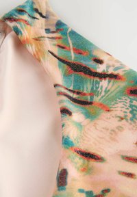 Tkanina wielobarwna z abstrakcyjnymi wzorami w odcieniach niebieskiego, różowego i czerwonego; gładka tekstura z lekkim połyskiem; posiada różowy panel boczny.