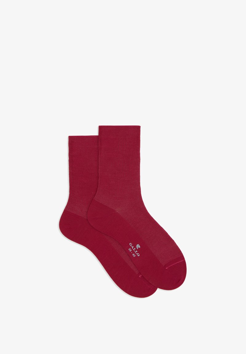 Calze di cotone rosse con un design a coste, dotate di talloni e punte rinforzati. Taglie indicate sulla suola. Texture liscia e cuciture uniformi.